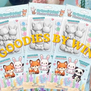 Könnte beinhalten: Drei My Kawaii Animal Gips-Malsets in transparenter Kunststoffverpackung. Jedes Set enthält weiße Gipsfiguren, einen kleinen Pinsel und Farbtöpfe. Die Verpackung zeigt Illustrationen von einem Fuchs, einem Hasen und einem Panda.