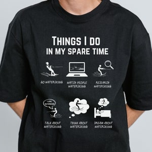 May include: Black t-shirt with white text that reads "Things I do in my spare time". The shirt features six illustrations of a person waterskiing, with captions such as "Go Waterskiing", "Watch People Waterskiing", "Research Waterskiing", "Talk About Waterskiing", "Think About Waterskiing", and "Dream About Waterskiing".