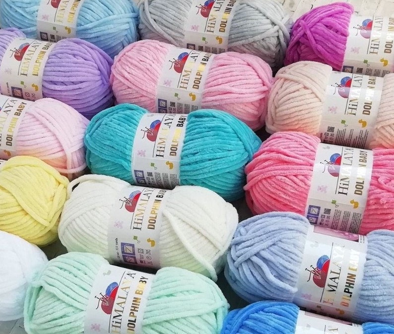 May include: Assortment of colorful yarn skeins in various pastel shades, including pink, blue, green, yellow, and white. The yarn is soft and fluffy, perfect for knitting or crocheting baby blankets, sweaters, and other projects. Each skein features the brand name "Himalaya" and the text "Dolphin Baby".