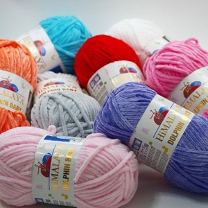 May include: Assortment of colorful yarn skeins in various shades of pink, blue, orange, gray, red, and purple. The yarn is soft and fluffy, perfect for knitting or crocheting baby blankets or other projects. Each skein has a label that reads "Himalaya Dolphin Baby".