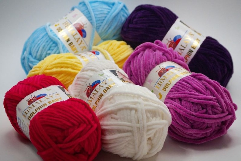 May include: Assortment of colorful yarn skeins in various shades of blue, yellow, white, red, and purple. The yarn is soft and fluffy, perfect for knitting or crocheting baby blankets or other projects.
