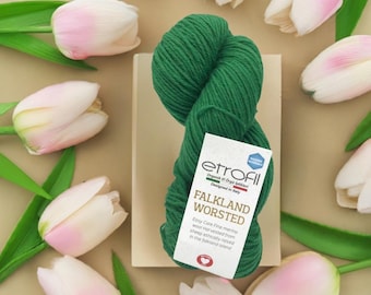 May include: A skein of vibrant green Falkland Worsted wool yarn with a white label, surrounded by pink and white tulips. The label reads "etrofil" and "FALKLAND WORSTED". The yarn is designed in Italy and harvested from ethically raised sheep.