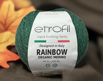 May include: A ball of green etrofil Rainbow Organic Merino yarn. The label reads "Designed in Italy" and lists the weight as 50 grams and 150 meters. The yarn is 75% organic merino wool and 25% polyamide.