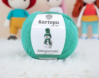 May include: A ball of teal Kartopu Amigurumi yarn with a label featuring a snowman wearing a green hat and scarf. The label also includes the text "Kartopu since 1952" and "Amigurumi". The yarn ball weighs 50 g and is 165 m long.
