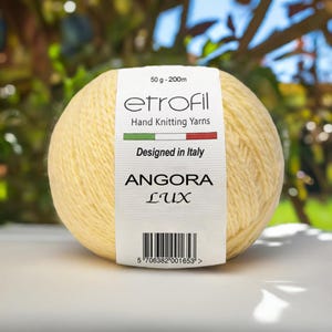 May include: A ball of yellow Angora Lux hand knitting yarn by etrofil. The label reads "Designed in Italy" and includes a barcode. The ball weighs 50 g and has 200 m of yarn.