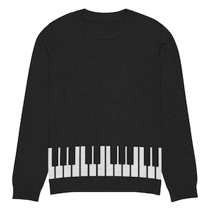 Puede incluir: Un suéter negro de manga larga con un diseño de teclado de piano blanco en la parte inferior.