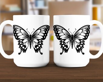 May include: Two white ceramic mugs with black butterfly designs. The butterflies have black and white polka dots on their wings.