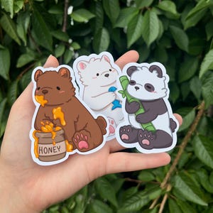 May include: Three cartoon bear stickers. A brown bear with a pot of honey, a white polar bear holding a blue fish, and a black and white panda bear holding a piece of bamboo.