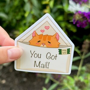 May include: A white envelope with a cute orange cat peeking out of the top. The envelope has a red heart and the text "You Got Mail!" on the front.