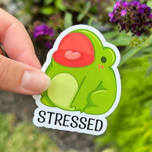 May include: A green frog sticker with a red mouth and the word "STRESSED" printed below it.