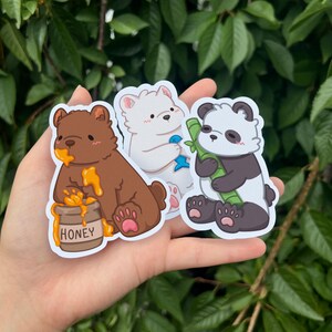 May include: Three cartoon bear stickers. A brown bear with a pot of honey, a white polar bear holding a blue fish, and a black and white panda bear holding a piece of bamboo.