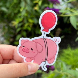 May include: A pink pig sticker with a red balloon tied to its tail. The pig has a cute cartoon face and is holding onto the balloon string.