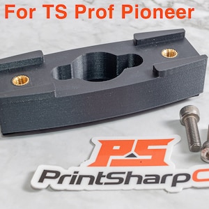 Może przedstawiać: Czarny uchwyt drukowany w 3D z dwoma wkładkami mosiężnymi i dwoma srebrnymi śrubami. Uchwyt jest oznaczony "For TS Prof Pioneer" i ma naklejkę z tekstem "PrintSharpCo".
