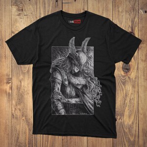May include: A black short-sleeve t-shirt featuring a white line-art graphic of a figure wearing a winged helmet and armor with long flowing hair. The design is enclosed in a rectangular frame. The brand name TAGHUB is printed in white and red at the neck.