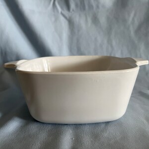 May include: White ceramic baking dish with two handles. The dish is square and has a smooth, glossy finish.