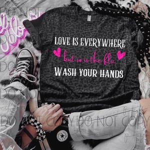 May include: A black t-shirt with a leopard print design. The shirt has white text that reads "LOVE IS EVERYWHERE but so is the flu WASH YOUR HANDS".