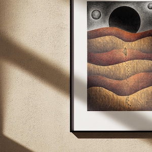 May include: A framed black and white illustration of a dark, round moon over a landscape of layered, brown hills. Two smaller, white moons are visible in the sky.