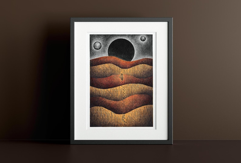 May include: A framed print of a black and white illustration depicting a lone figure walking across a landscape of rolling hills under a dark sky with three celestial bodies.