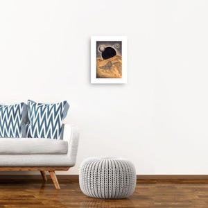 May include: A framed print of a black and white illustration of a landscape with a large black sphere in the sky.
