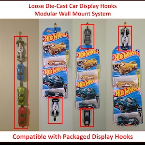 May include: A modular wall mount system for displaying die-cast cars. The image shows several die-cast cars hanging on hooks. The text at the top says "Loose Die-Cast Car Display Hooks Modular Wall Mount System." The text at the bottom says "Compatible with Packaged Display Hooks."