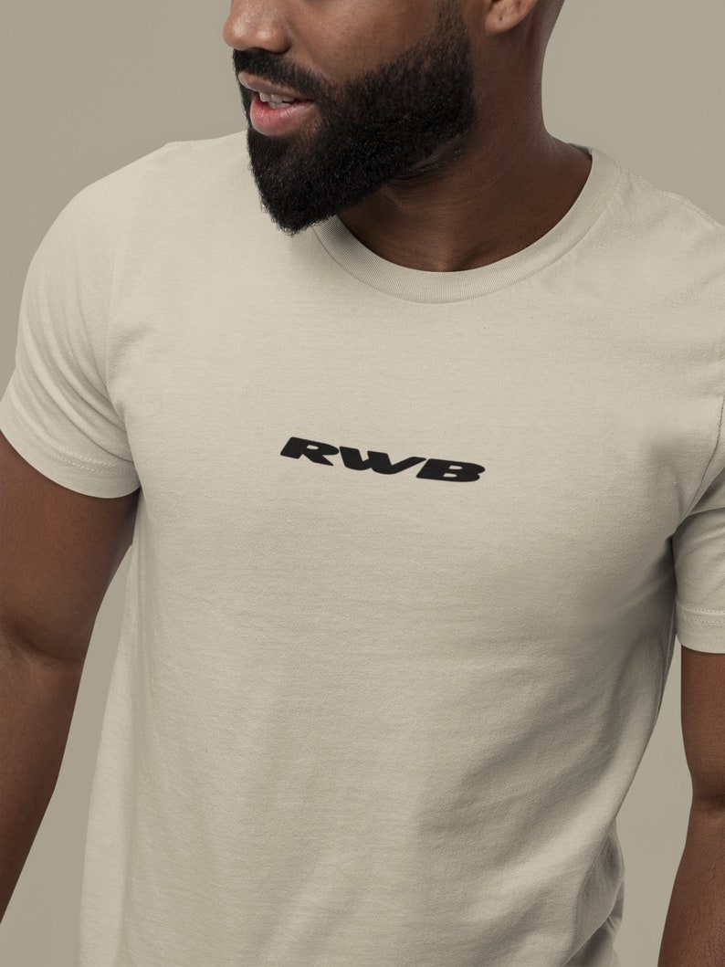 May include: A cream-colored t-shirt with the black letters "RWB" printed across the chest. The shirt has a crew neck and short sleeves. The fabric appears to be a soft, breathable material.