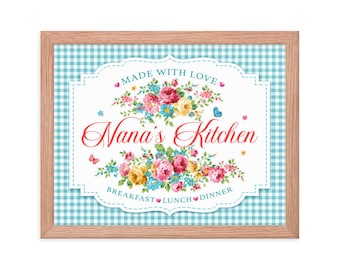 May include: A framed sign with a blue and white gingham background. The sign features a white banner with a floral design and the text "Made with Love" and "Nana's Kitchen". The banner also includes the words "Breakfast", "Lunch", and "Dinner".