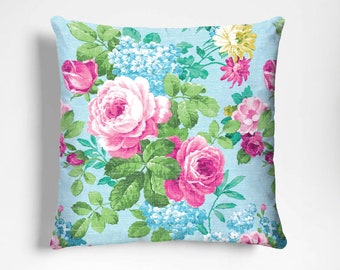 May include: A light blue throw pillow with a floral pattern featuring pink roses, green leaves, and blue flowers.