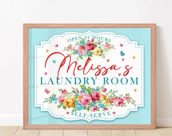 May include: A light blue sign with a white border and floral design. The sign says "Open 24 Hours" and "Melissa's Laundry Room" with the words "Self-Serve" at the bottom.