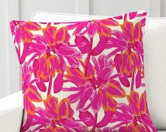 May include: Square decorative pillow with a vibrant floral pattern in shades of pink and orange on an off-white background. The pillow is placed on a white sofa. The text "Country Living Style" is visible at the bottom.