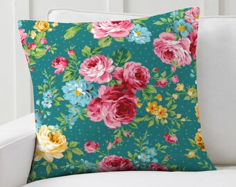 May include: Teal blue throw pillow with a floral pattern featuring pink, red, yellow, and blue flowers.