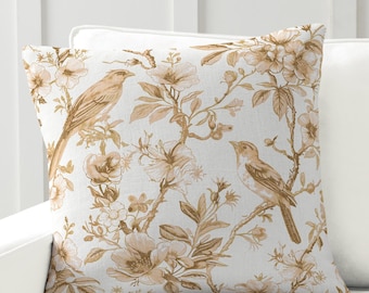 May include: A decorative throw pillow with a beige background and a floral pattern featuring brown birds and flowers. The pillow is on a white couch. "Country Living Style" and "Nature-Inspired Wellness Decor" are printed below the pillow.