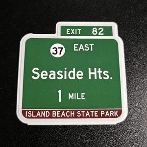 May include: Green and white highway sign with the text "Exit 82", "37 East", "Seaside Hts.", "1 Mile", and "Island Beach State Park".