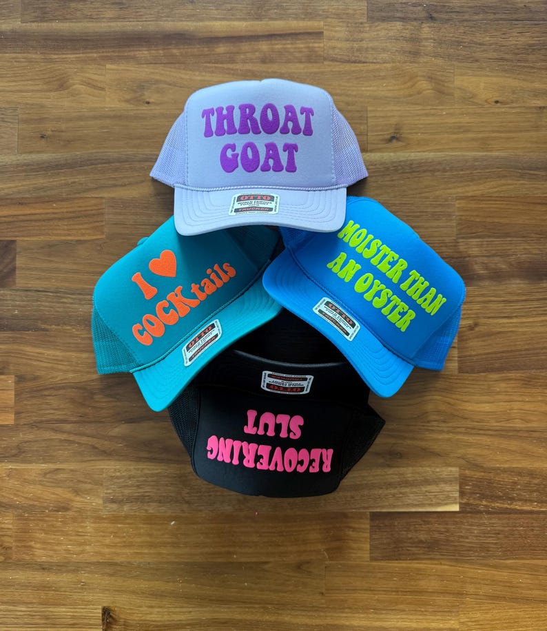 May include: Four trucker hats with mesh backs and foam fronts. The top hat is light purple with purple text reading THROAT GOAT. The left hat is teal with orange text reading I HEART COCKtails. The right is blue with lime text MOISTER THAN AN OYSTER. The bottom is black with pink text RECOVERING SLUT.