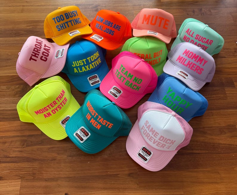May include: A collection of twelve colorful foam trucker hats featuring various phrases in bold lettering. The hats come in shades of yellow, orange, pink, blue, green, and white, each with a structured front panel and mesh back, displaying text like Mute, Yappy Hour, and Throat Coat.