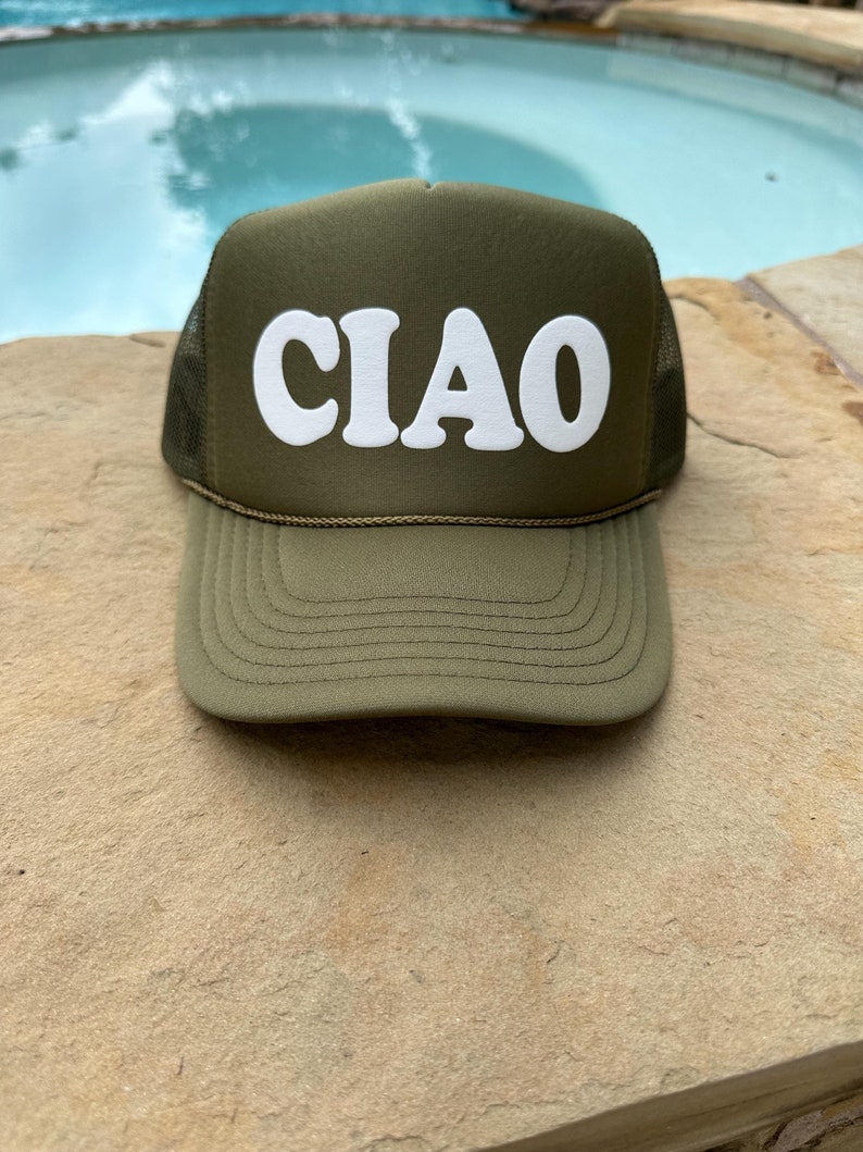 May include: A green trucker hat with a white "CIAO" logo in a retro font. The hat is made of a mesh material and has a curved brim.