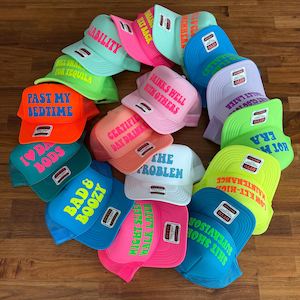 May include: A collection of colorful trucker hats featuring various phrases in bold lettering, including Past My Bedtime, I Love Dad Bods, Bad & Boozy, Drinks Well With Others, Certified Day Drinker, The Problem, Might Sleep Walk Later, and Shit Show Supervisor.