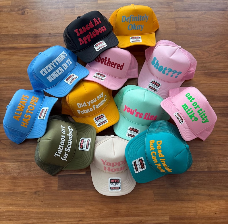 May include: A collection of eleven colorful trucker hats featuring various embroidered phrases including Tased At Applebees, Definitely Okay, EVERYTHING'S BIGGER IN TX, unbothered, Shot???, ALWAYS HAS TO PEE, Did you say Potato Famine?, you're fine, oat or titty milk?, Tattoos are Scumbags, Yappy Hour, and Dead Inside But Can Party.