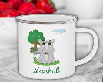 Könnte beinhalten: Weiße Email Tasse mit silbernem Rand, die ein Cartoon-Nashorn in einer grünen Waldlandschaft zeigt. Die Tasse trägt den Namen "Marshall" in Grün unter dem Bild.