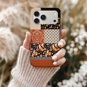 Puede incluir: Funda de teléfono de estilo patchwork con varios diseños. La funda incluye secciones con un patrón damasco, motivos florales e imágenes de zorros. La paleta de colores incluye tonos marrones, negros y naranjas.