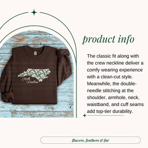 May include: A brown sweatshirt featuring a floral design in the shape of North Carolina. The text "North Carolina" is below the design. The sweatshirt has a crew neckline and long sleeves. The words "flowers, feathers & fur" are at the bottom.
