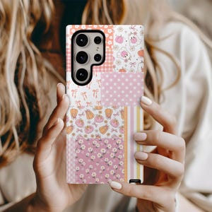 May include: A patchwork phone case featuring various patterns in pink, orange, and white. Designs include pumpkins, stars, flowers, and bows. The case has a camera cutout and a black border.