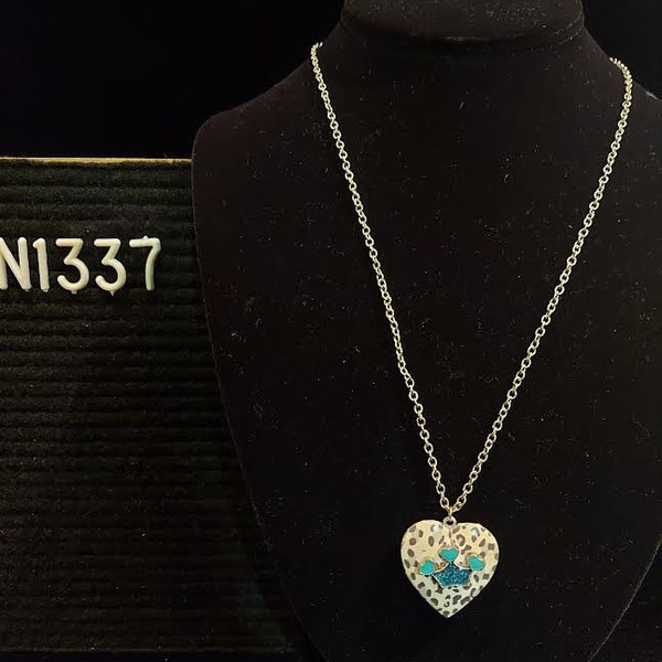 Heart shaped locket has grey "chamo" pattern and aqua medallion with 3 hearts and glittery crown shape.