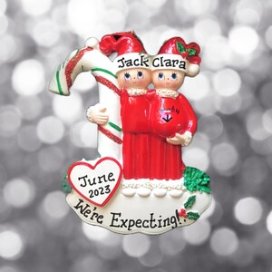 Pareja de elfos de bastón de caramelo embarazadas con gorros de Papá Noel. Adorno navideño personalizado. Estamos esperando. Anuncio de embarazo. Futuros padres.