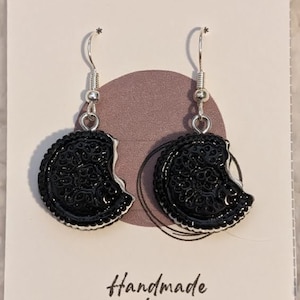 Könnte beinhalten: Ein Paar schwarze und silberne Ohrringe in Form eines angebissenen Kekses. Die Ohrringe befinden sich auf einer weißen Karte mit dem Text "Handmade & Co." und "Handmade by Harris".