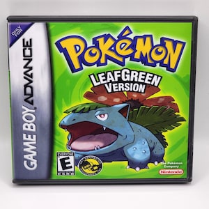 Puede incluir: Cartucho de juego Game Boy Advance para Pokemon Edición Verde Hoja. El cartucho es negro con una imagen verde, roja y azul de un personaje Pokemon en la parte delantera. El texto "Pokemon Edición Verde Hoja" está impreso en blanco en la parte delantera del cartucho.