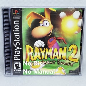 May include: A PlayStation game case for Rayman 2: Great Escape. The case is black with a green, yellow, and red image of Rayman on the front. The text "Rayman 2" is in large, yellow letters. The text "Great Escape" is in smaller, white letters. The ESRB rating of "E" for Everyone is in the bottom left corner. The text "No Disc" and "No Manual" is written in black on the front of the case.