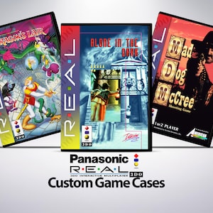 Könnte beinhalten: Drei kundenspezifische Spielhüllen für das interaktive Multiplayer-System Panasonic REAL 3DO. Die Hüllen zeigen Grafiken aus den Spielen "Dragon's Lair", "Alone in the Dark" und "Mad Dog McCree". Die Hüllen sind schwarz mit farbenfrohen Spielgrafiken.