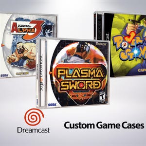 May include: Three Sega Dreamcast game cases with custom artwork. The cases are white with a clear plastic window to show the game disc. The games are Street Fighter Alpha 3, Power Stone 2, and Plasma Sword: Nightmare of Bastet.