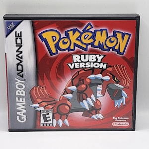May include: A red and black Game Boy Advance game cartridge for Pokemon Ruby Version. The front of the cartridge features a cartoon image of a red and grey Pokemon with white claws. The text "Pokemon Ruby Version" is printed in white on a red background.