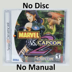 May include: A Sega Dreamcast game case for Marvel vs. Capcom 2. The case is clear plastic and shows the game's cover art featuring characters from Marvel and Capcom. The text "Sega Dreamcast", "Marvel vs. Capcom 2", "CAPCOM", and "TEEN" is visible on the case. The case is missing the game disc and manual.